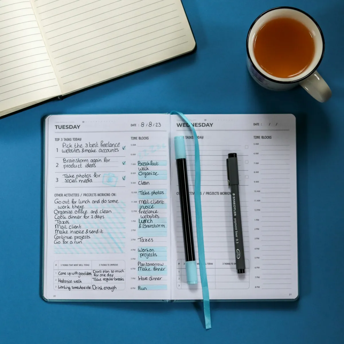 Carnet ouvert avec un stylo et une tasse de thé